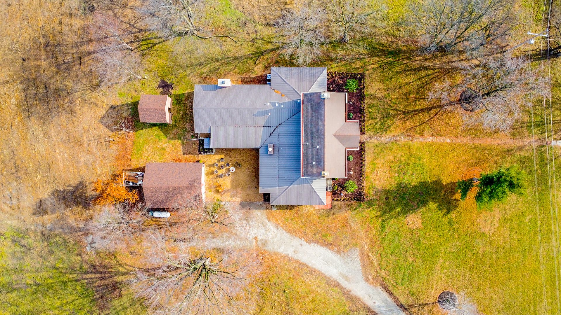 An aerial view shows a sprawling property with a main house, outbuildings, and a winding driveway, surrounded by green and autumn-toned foliage.