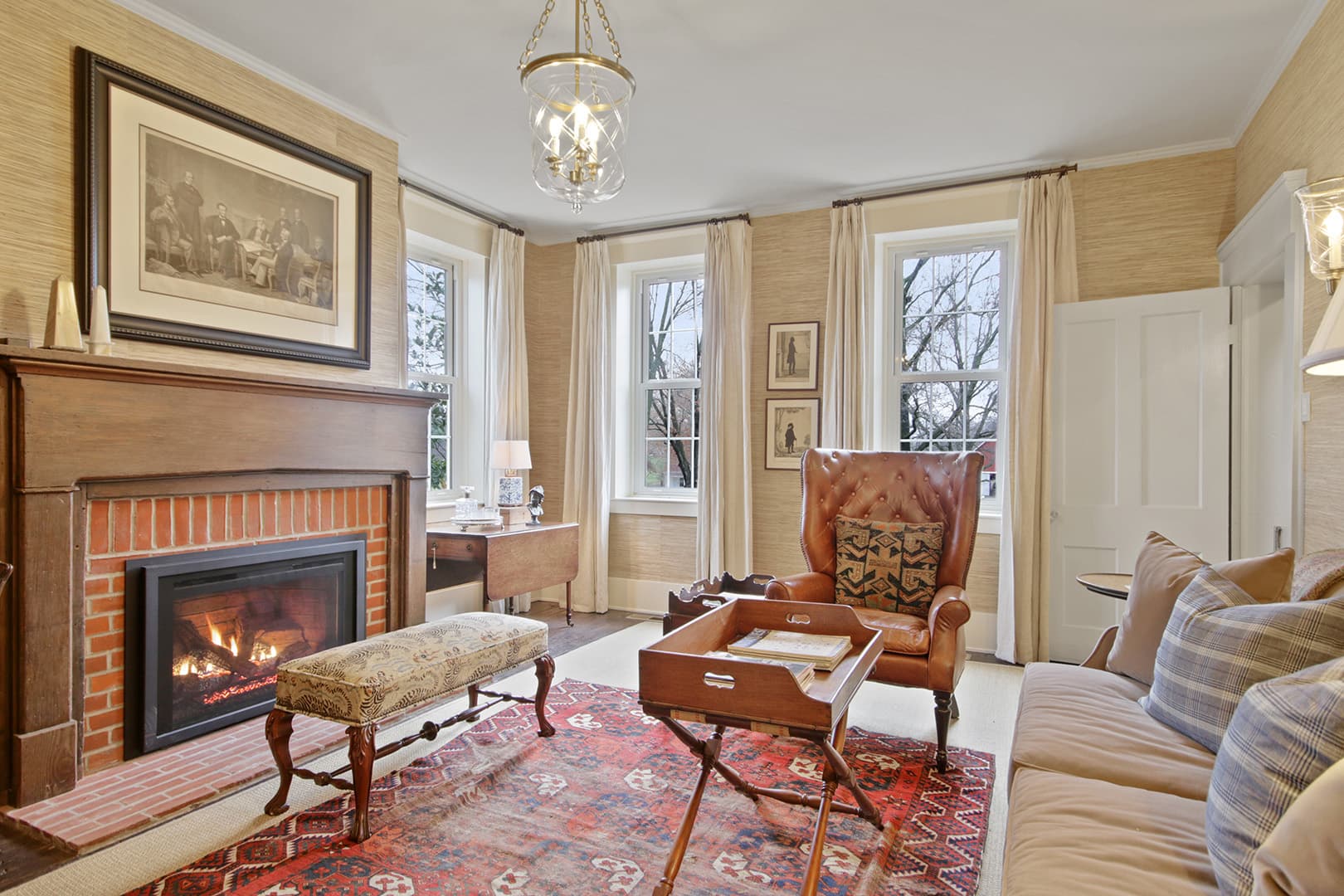 Cozy traditional living room with fireplace, armchair, sofa, and lots of natural light.